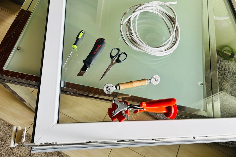 Werkzeug und neues Dichtungsprofil auf einem Fensterflügel